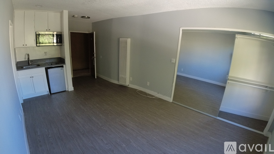 A room with a kitchenette and a sliding glass door leading to a balcony.
