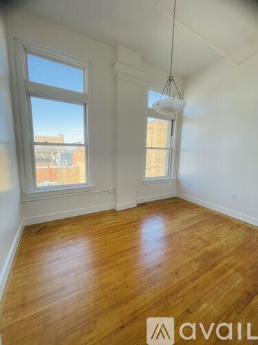 A room with wooden floors and two windows.