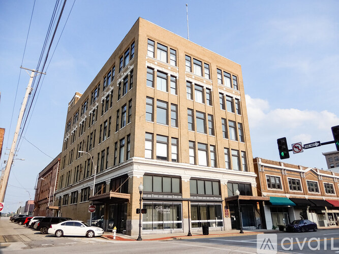 A large tan building with many windows sits on a street corner.