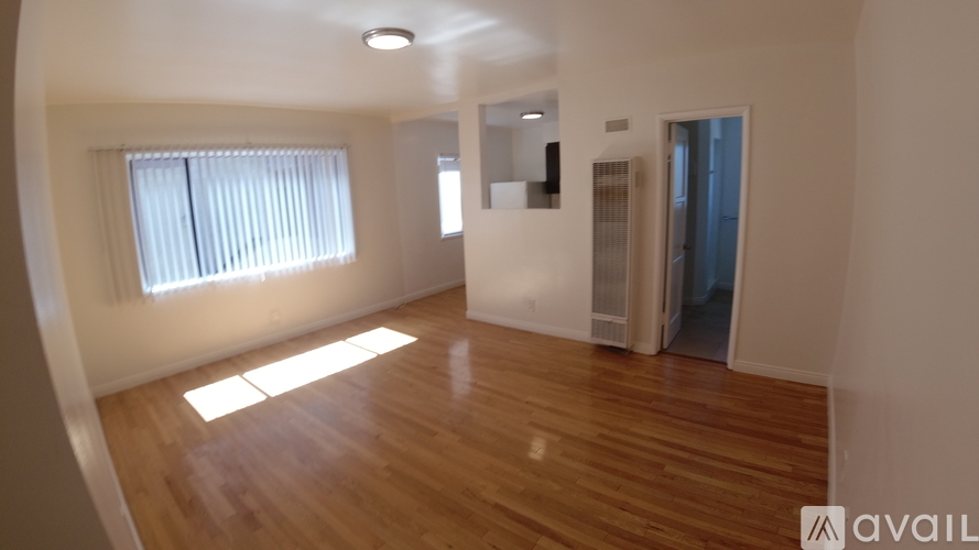 A room with wooden floors and a window with blinds.