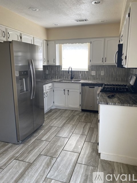 A kitchen with a stainless steel refrigerator and white cabinets.