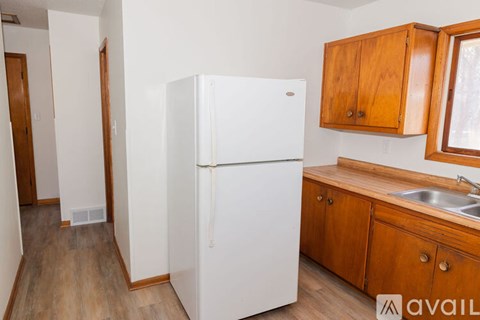 A white refrigerator in a kitchen with wooden cabinets.