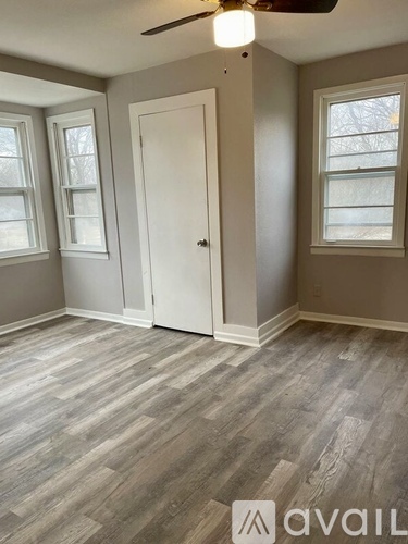 A room with a white door and grey flooring.