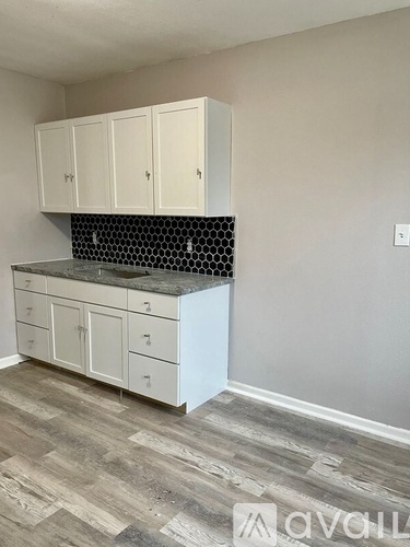 A kitchen with white cabinets and a black and white tiled backsplash.