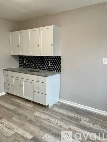 A kitchen with white cabinets and a black and white tiled backsplash.
