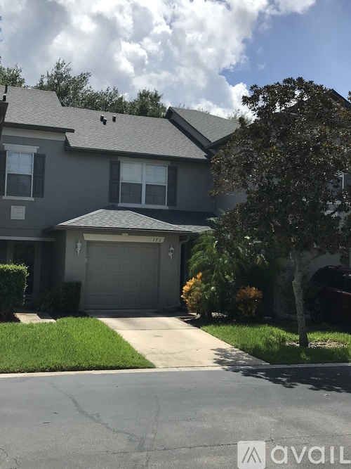 A house with a grey garage door and a tree in front.