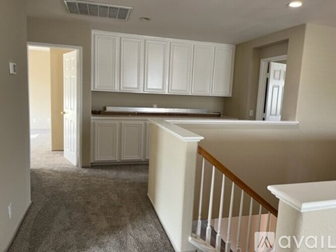 A kitchen with white cabinets and a carpeted floor.