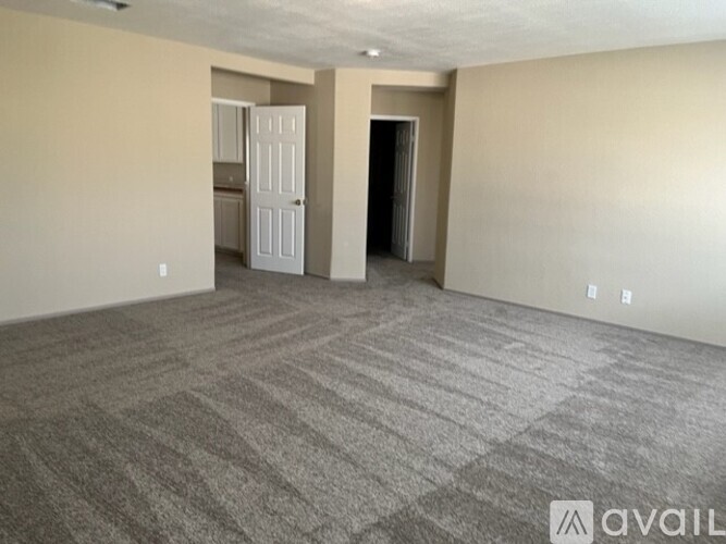 A spacious room with a carpeted floor and two open doors.