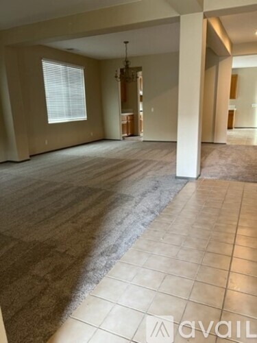 A spacious room with a carpeted floor and a tiled floor.