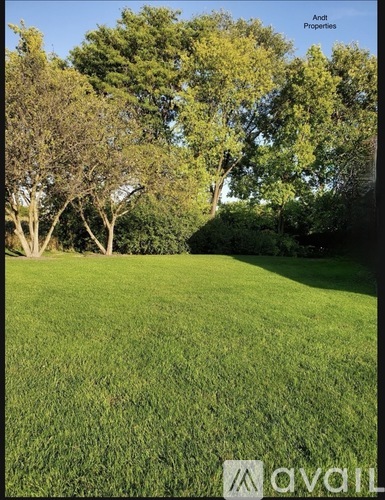 A grassy field with trees in the background and a sign that says "Andi Properties".