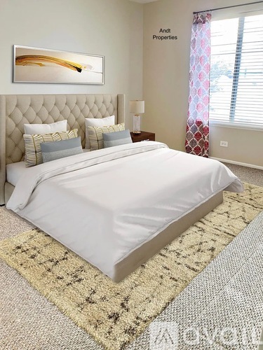 A bedroom with a large bed and a painting on the wall.