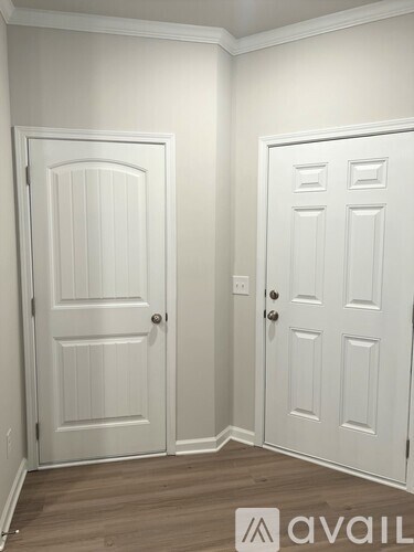 Two white doors in a room with wooden floors.