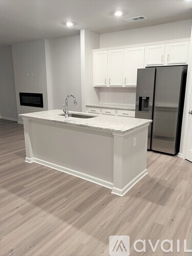 A kitchen with a white island and a refrigerator.