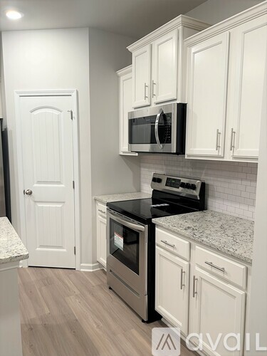 A kitchen with white cabinets and a black microwave above the stove.