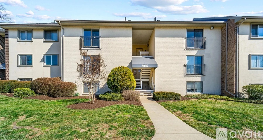 A modern apartment building with a well-maintained lawn and a clear sky.
