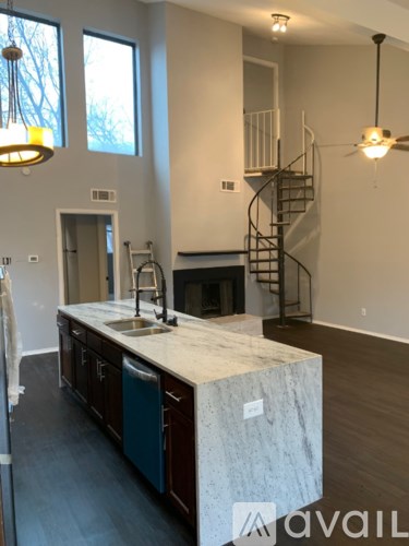A kitchen with a marble counter top and a staircase in the background.