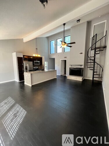 A spacious living room with a fireplace and a spiral staircase.
