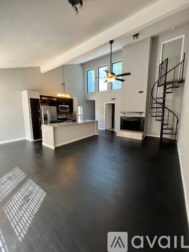 A spacious living room with a fireplace and a spiral staircase.