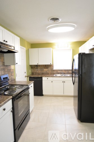 A kitchen with black appliances and white cabinets.