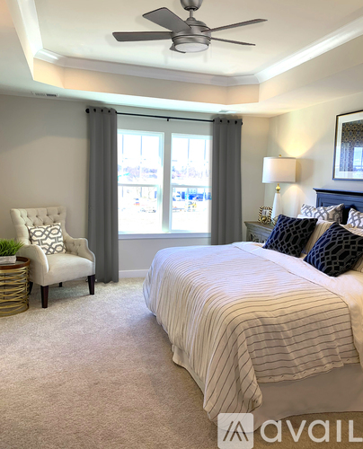 A bedroom with a large bed and a chair by the window.