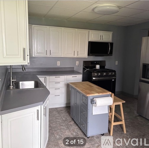 A kitchen with white cabinets and a wooden island.