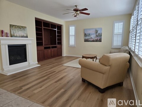 A living room with a fireplace, a chair, and a painting on the wall.