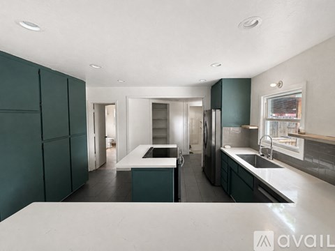 A modern kitchen with dark green cabinets and a white countertop.