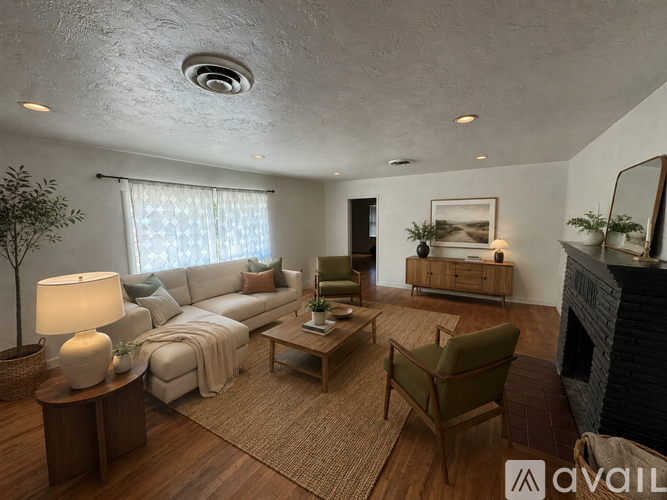 A living room with a white sofa, a green armchair, a wooden coffee table, and a fireplace.