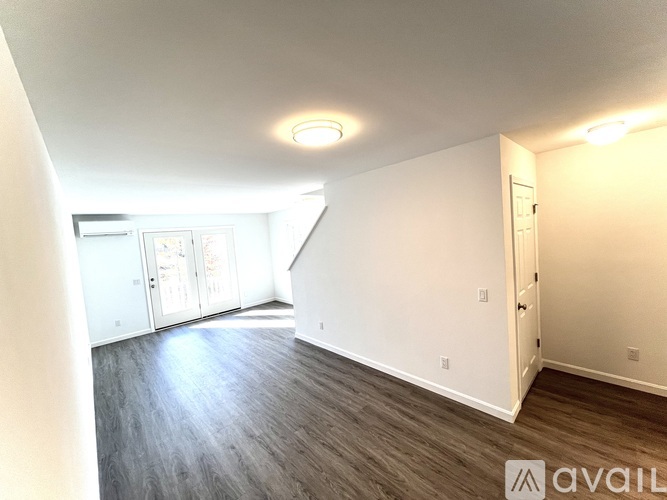 A spacious room with wood flooring and white walls.