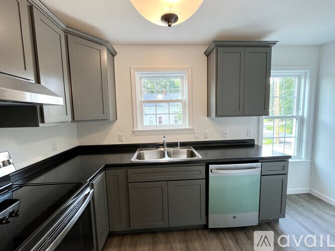 A kitchen with a black countertop and grey cabinets.