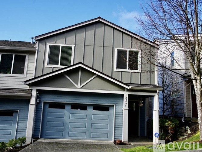 A two-story house with a grey exterior and a blue garage door.