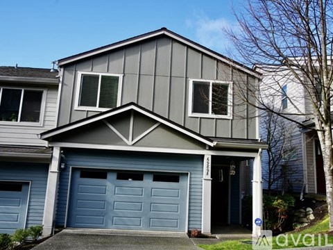 A two-story house with a grey exterior and a blue garage door.