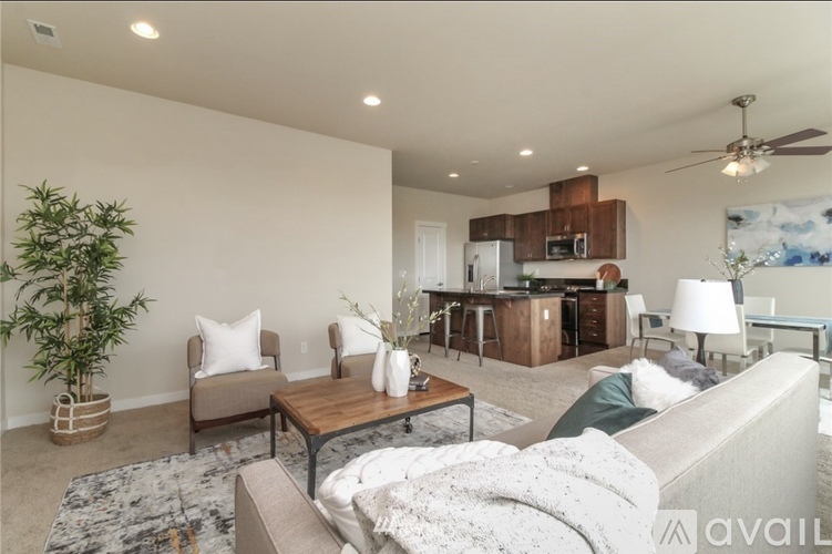 A living room with a grey couch, a wooden coffee table, and a kitchen area in the background.