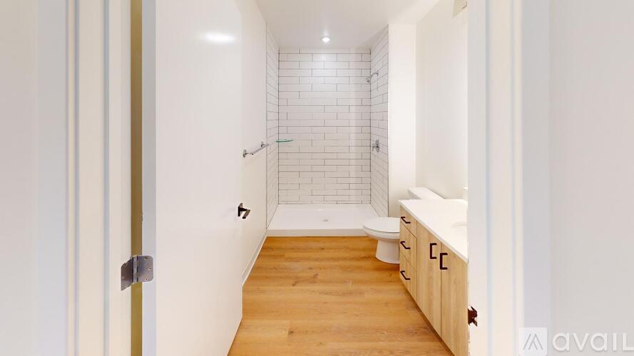 A bathroom with a white tiled shower and wooden floors.
