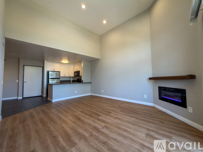 A spacious living room with wood flooring and a fireplace.