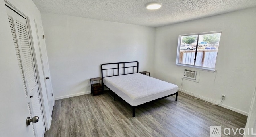 A bedroom with a bed, nightstand, and window.