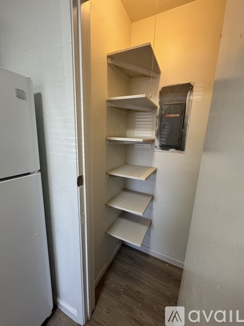 A white refrigerator is in a kitchen with a wall-mounted microwave.