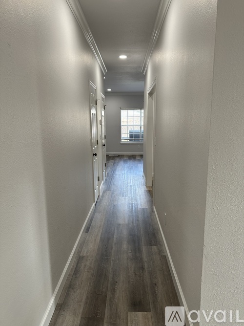 A long, narrow hallway with wood flooring and white walls.