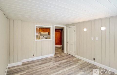 A room with wooden floors and white walls with a window and a door.