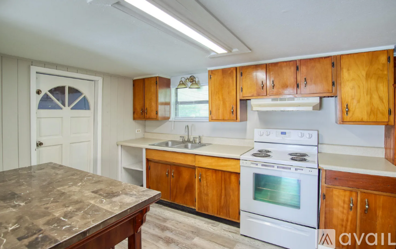A kitchen with wooden cabinets and a white stove top oven.