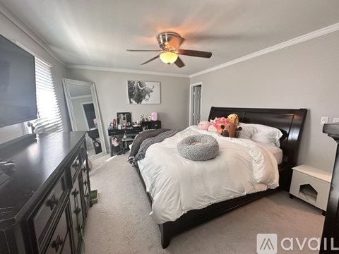A bedroom with a bed, dresser, and a ceiling fan.