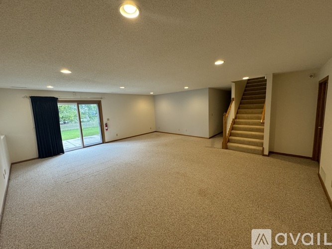A spacious room with a staircase and sliding glass doors.