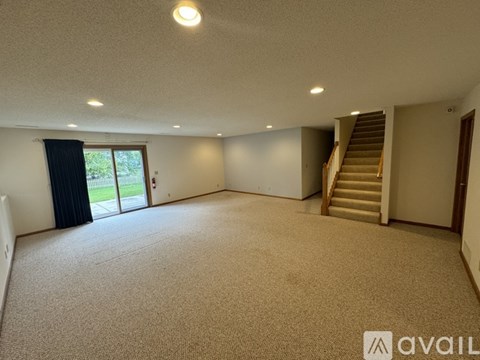 A spacious room with a staircase and sliding glass doors.