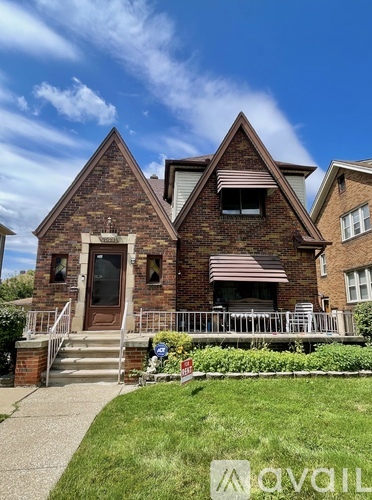 A brick house with a porch and a small garden in front.