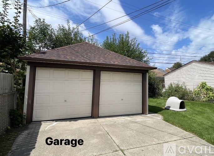 A two-car garage with a brown roof and white doors is labeled "Garage" on a concrete walkway.