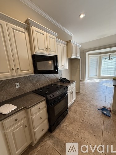 A kitchen with beige cabinets and a black stove top oven.