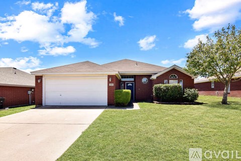 A house with a garage and a tree in front.