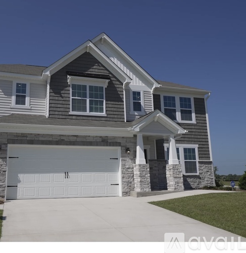 A two-story house with a garage and a driveway.