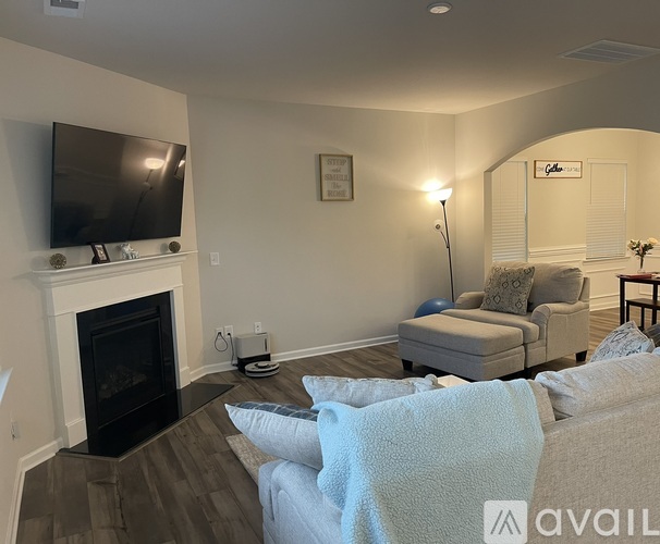 A living room with a fireplace and a television mounted above it.