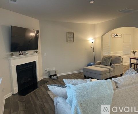 A living room with a fireplace and a television mounted above it.